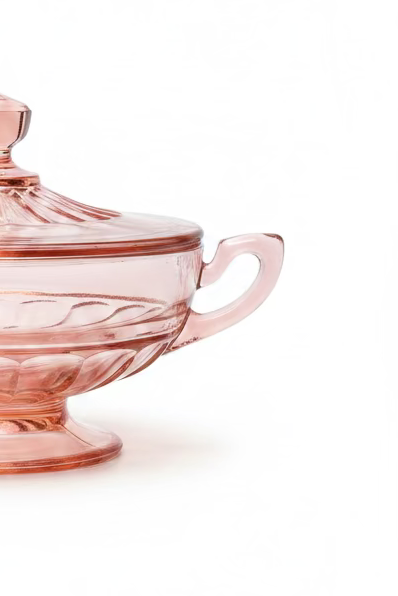 Close-up view of the ribbed pink depression glass bowl, showing the intricate details of the handle and pedestal base, against a white background.