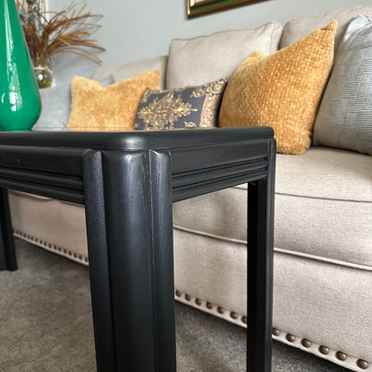 Side view of vintage black console table with fluted legs