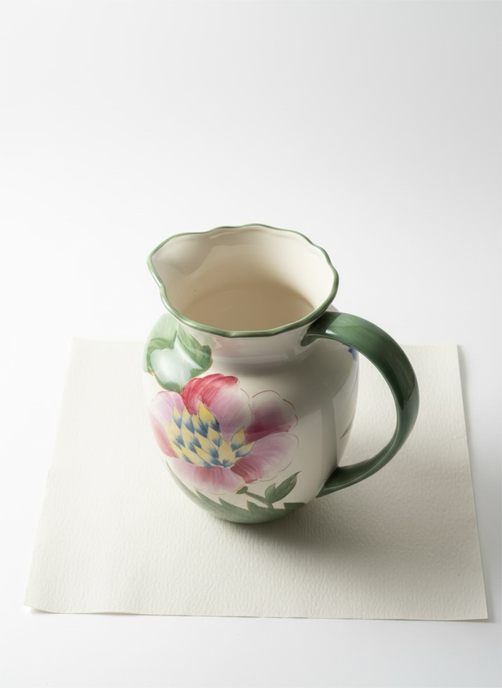 Decorative ceramic pitcher with floral design on a white background