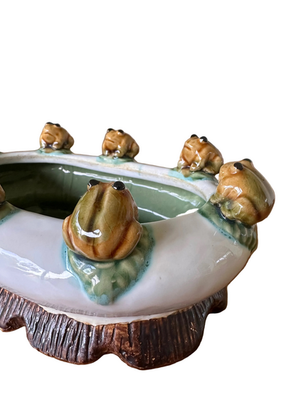 Detailed close-up of high-gloss glazed ceramic frogs on lily pads showing green glaze bleeding into white porcelain on a vintage mid-century planter.⁠