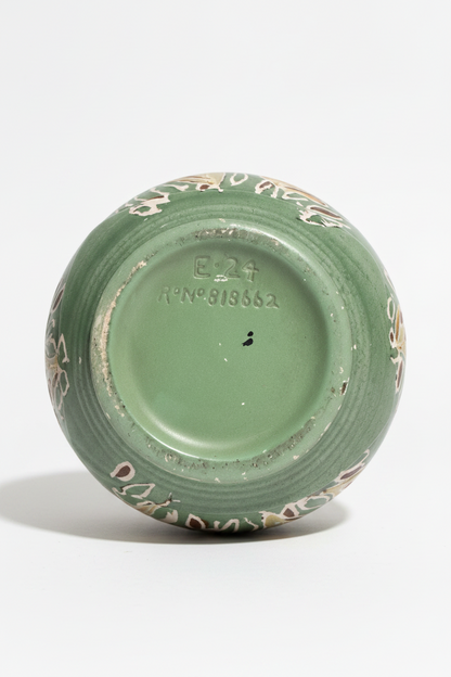Directly overhead view of the underside of a sage green ceramic vase. The unglazed circular base rim surrounds a smooth green center featuring clearly debossed registry marks that read "E-24" and "R° N° 818662".