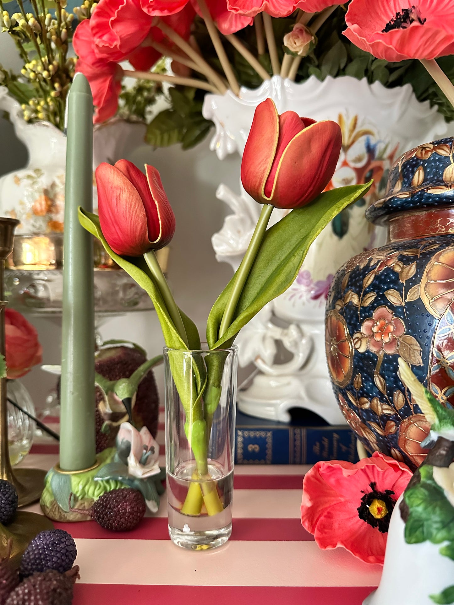 Decorative table setting with red tulips, a vase, and a decorative vase in the background.