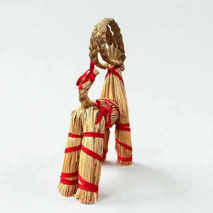 Straw dog toy with red ribbons on a white background