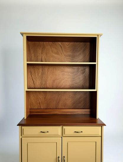 Two-piece yellow breakfront with open wood-backed shelves and lower drawers, styled in a cozy living room with a sofa, artwork, and patterned rug.