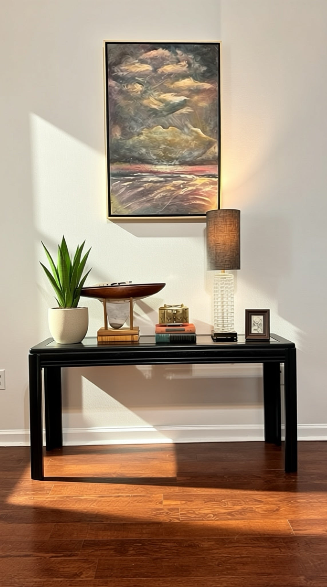 Modern black console table with decorative items, lamp, and plant for stylish home decor.