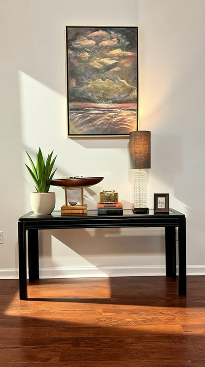Modern black console table with decorative items, lamp, and plant for stylish home decor.