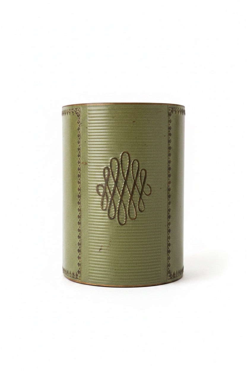 Front close-up view of a single vintage sage green leather bookend showing detailed ribbed texture, gold-embossed filigree border, and looped central emblem.