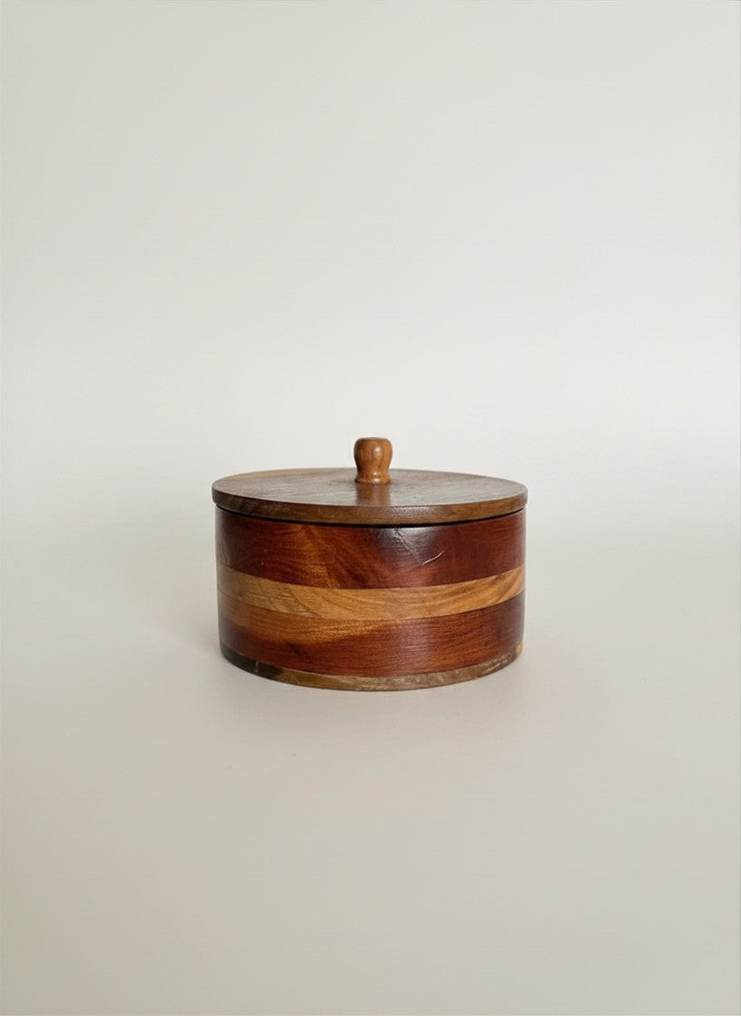 Side profile of a vintage circular lidded wood box showcasing alternating two-tone inlaid timber bands in walnut and honey tones.