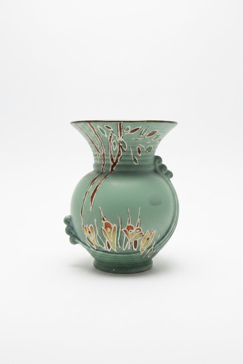 Front view of a vintage matte sage green ceramic vase against a clean white background. The vase features a bulbous body, a flared trumpet neck with fine horizontal ridges, and an embossed art deco ribbon detail winding down the side. Faint hand-painted floral accents in cream and burgundy decorate the base and upper rim.
