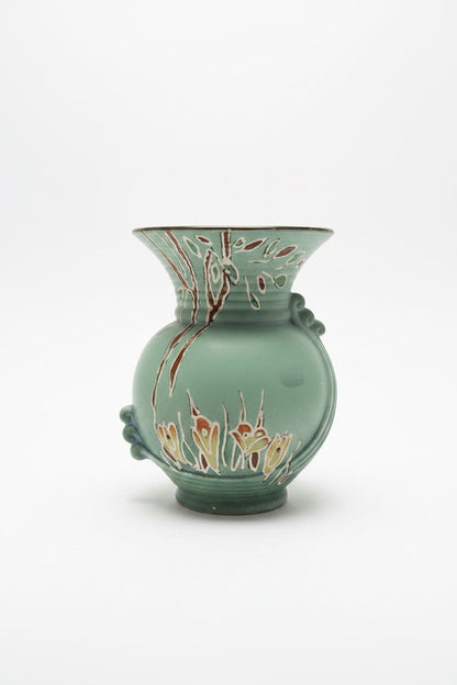 Front view of a vintage matte sage green ceramic vase against a clean white background. The vase features a bulbous body, a flared trumpet neck with fine horizontal ridges, and an embossed art deco ribbon detail winding down the side. Faint hand-painted floral accents in cream and burgundy decorate the base and upper rim.
