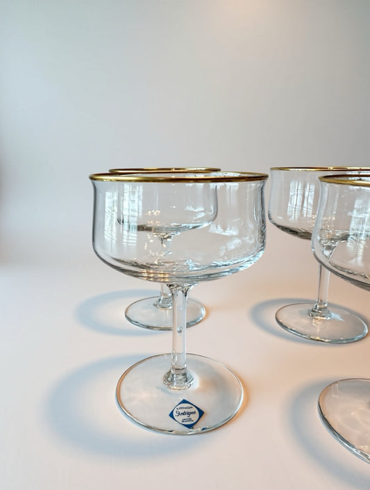 Clear glass goblets with gold rims on a white surface set a four mid-century modern Lennox Coupe’s