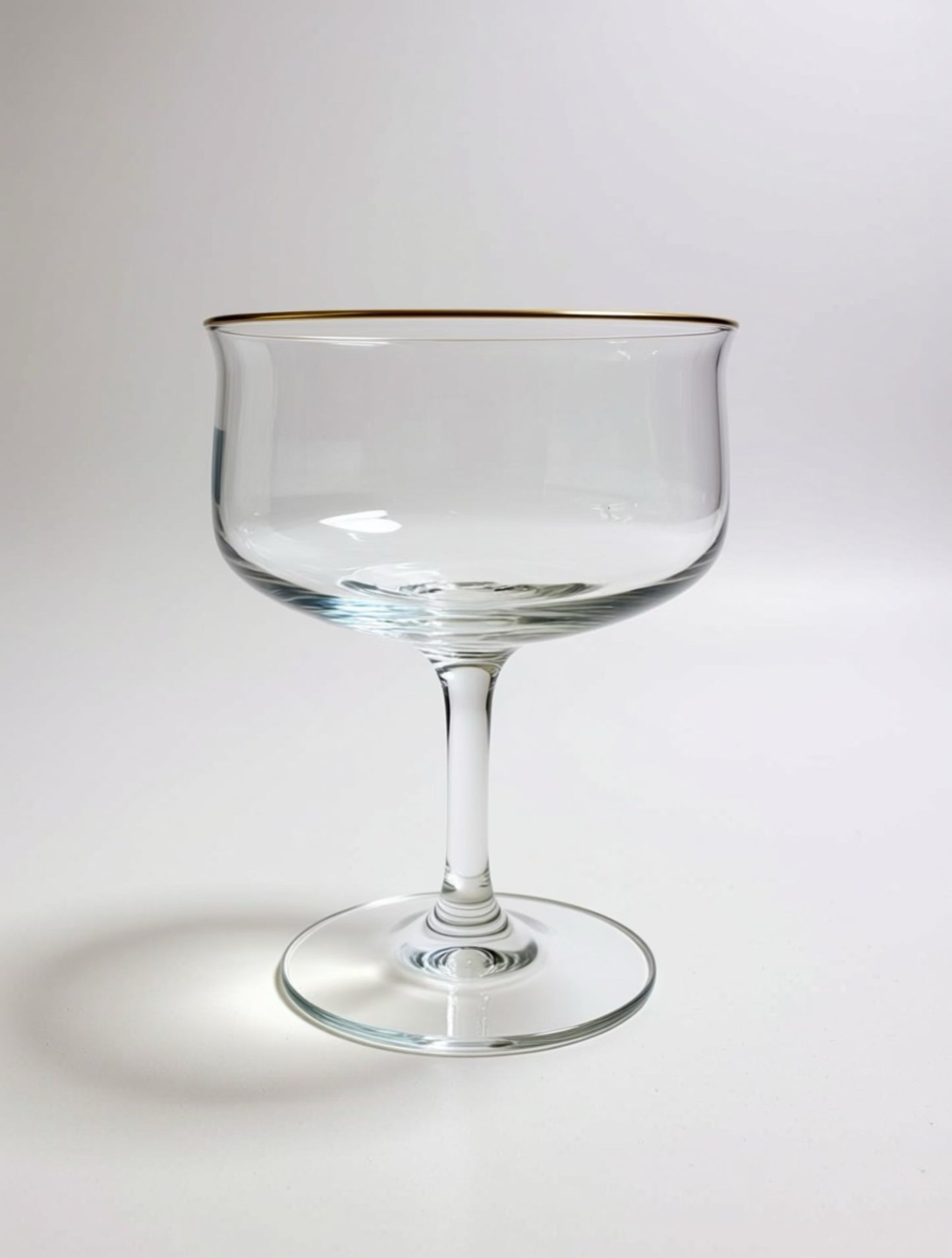 Clear glass with gold rim on a white background Image of single Lennox mid-century, modern coupe glass that belongs to a set of four in a vintage collection