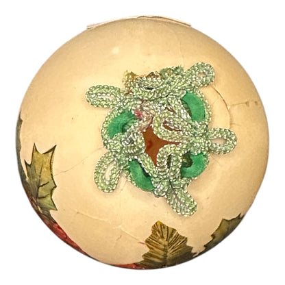 Decorative ball with green beaded design on a white background