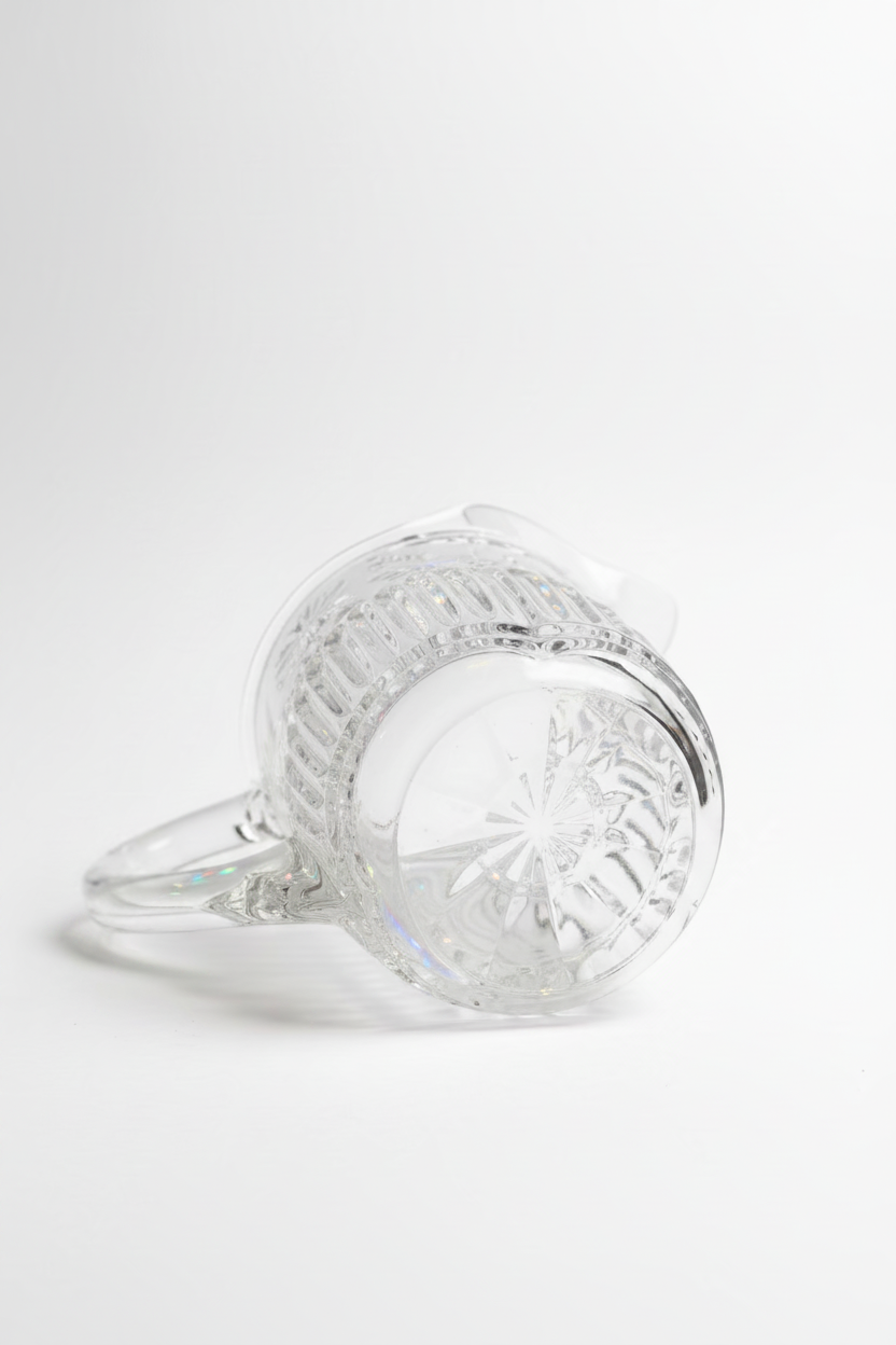  Bottom view of vintage mid-century pressed glass pitcher showing inset starburst cut pattern on heavy base with crosshatch diamond texture and molded glass handle, white background