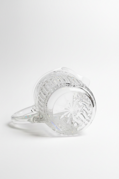  Bottom view of vintage mid-century pressed glass pitcher showing inset starburst cut pattern on heavy base with crosshatch diamond texture and molded glass handle, white background
