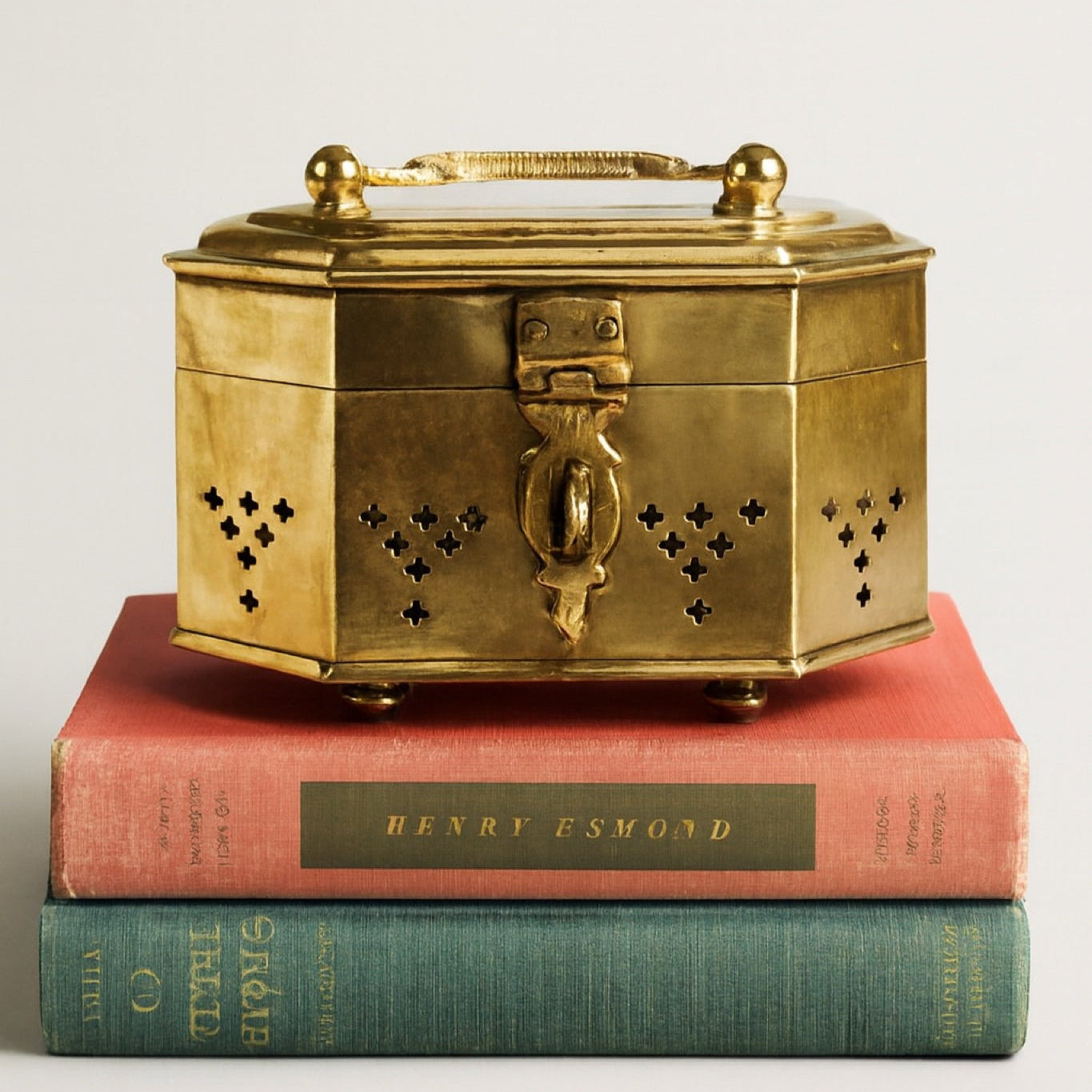 Brass box on top of two books with visible titles