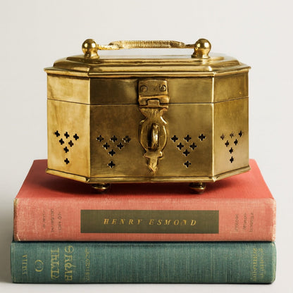 Brass box on top of two books with visible titles