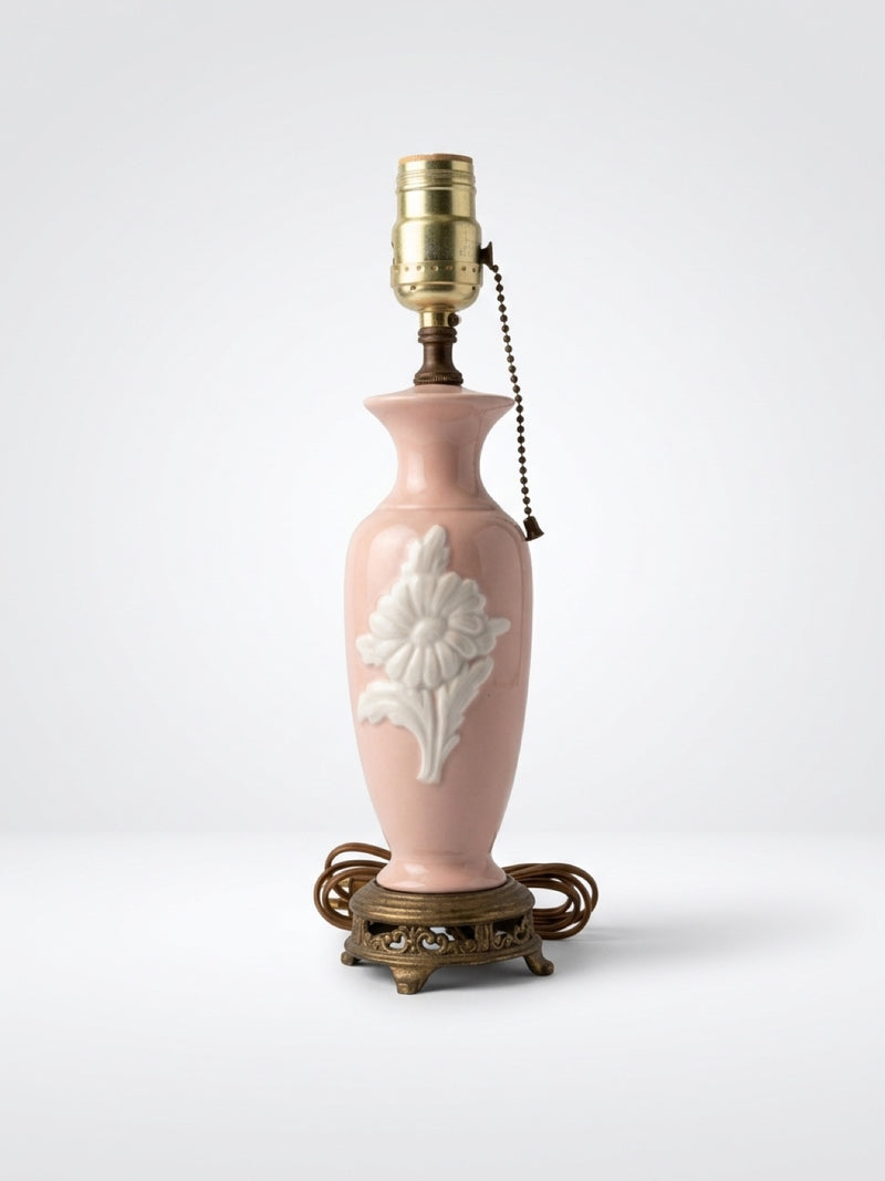 Vintage blush pink ceramic boudoir table lamp with embossed white flower relief, pull chain, and ornate brass footed base.