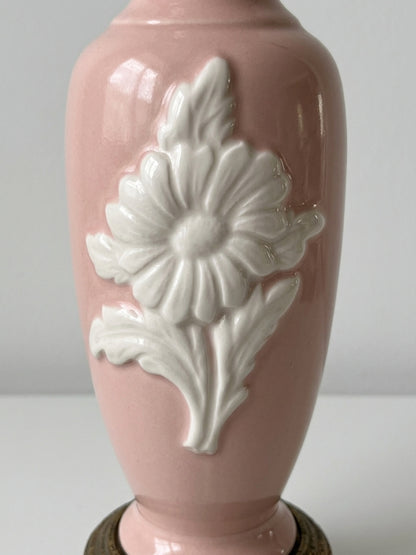Close-up detail of the white embossed floral motif on the glossy pink ceramic body of a vintage table lamp.