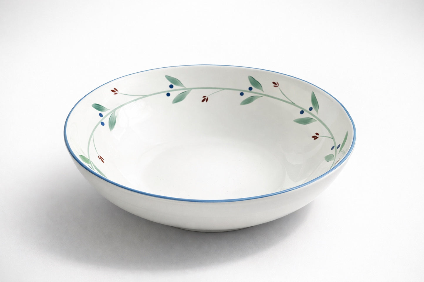 Dansk Portugal XL pasta bowl with botanical rim pattern of green leaves, blue berries, and red buds, photographed on white background for catalog or resale