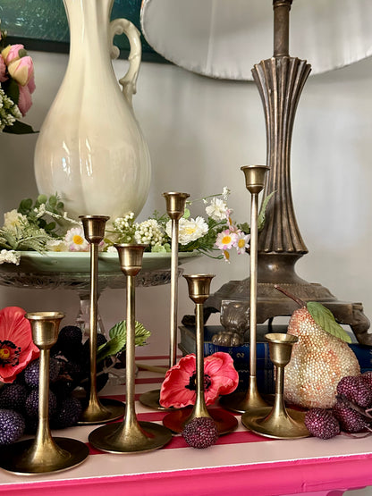 Decorative table setting with gold candlesticks, flowers, and a pink surface.