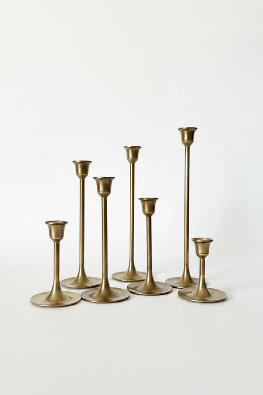 Decorative table setting with gold candlesticks, flowers, and a pink surface.