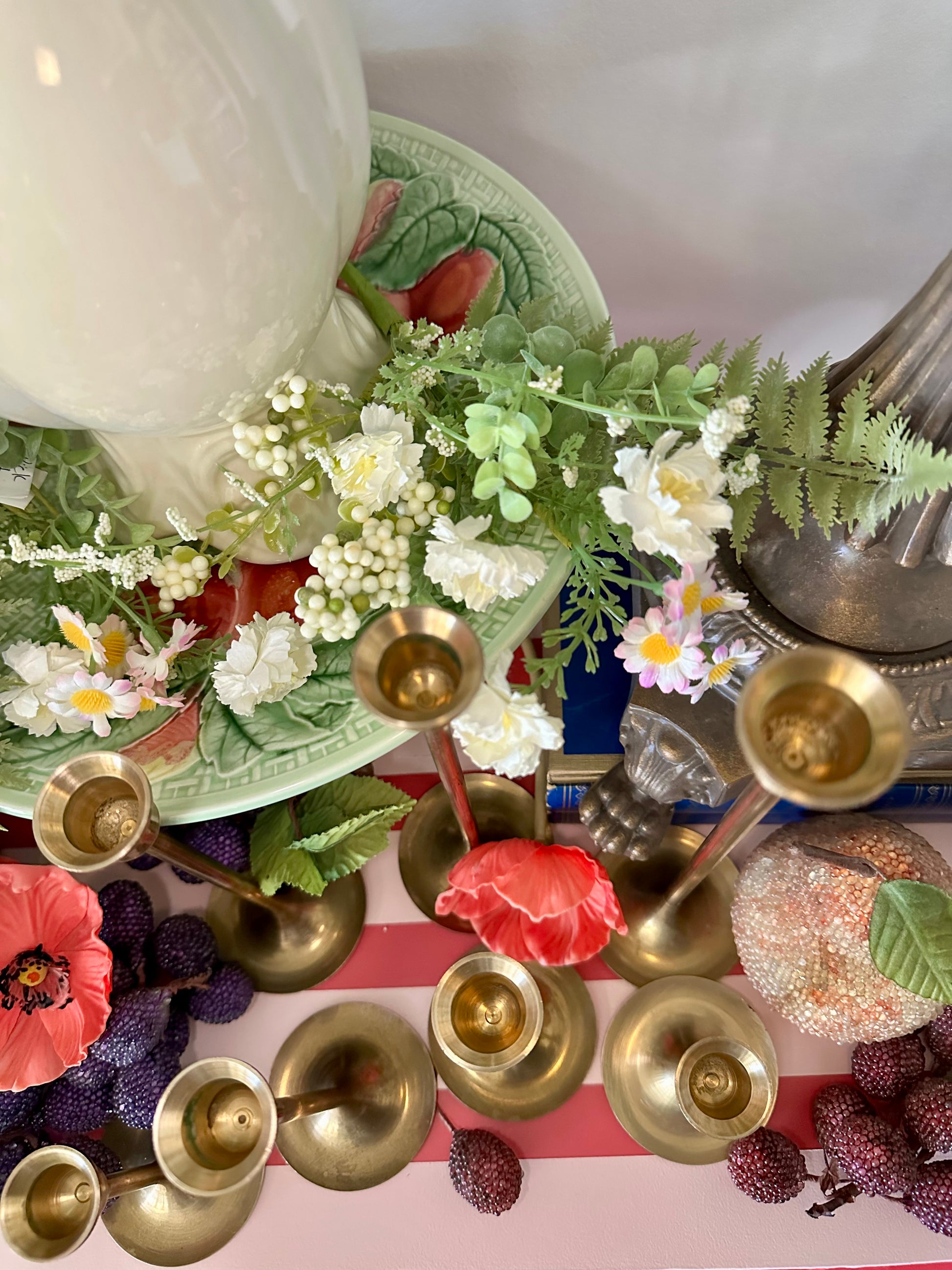 Decorative arrangement with flowers, candles, and a bowl on a striped surface.