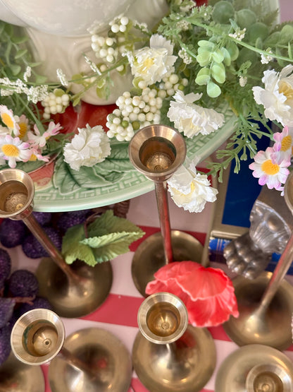 Decorative setup with brass candlesticks, flowers, and a colorful background