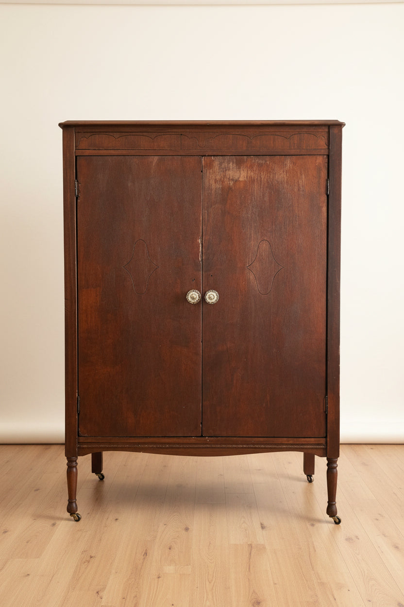 Wooden cabinet in a living room setting with a sofa and framed picture in the background.