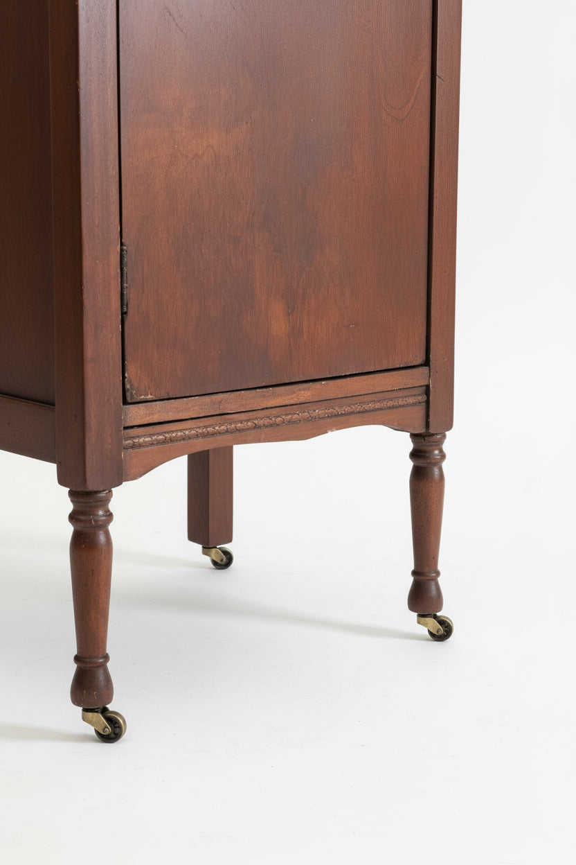 Close-up of a wooden cabinet with a decorative leg on a textured rug.