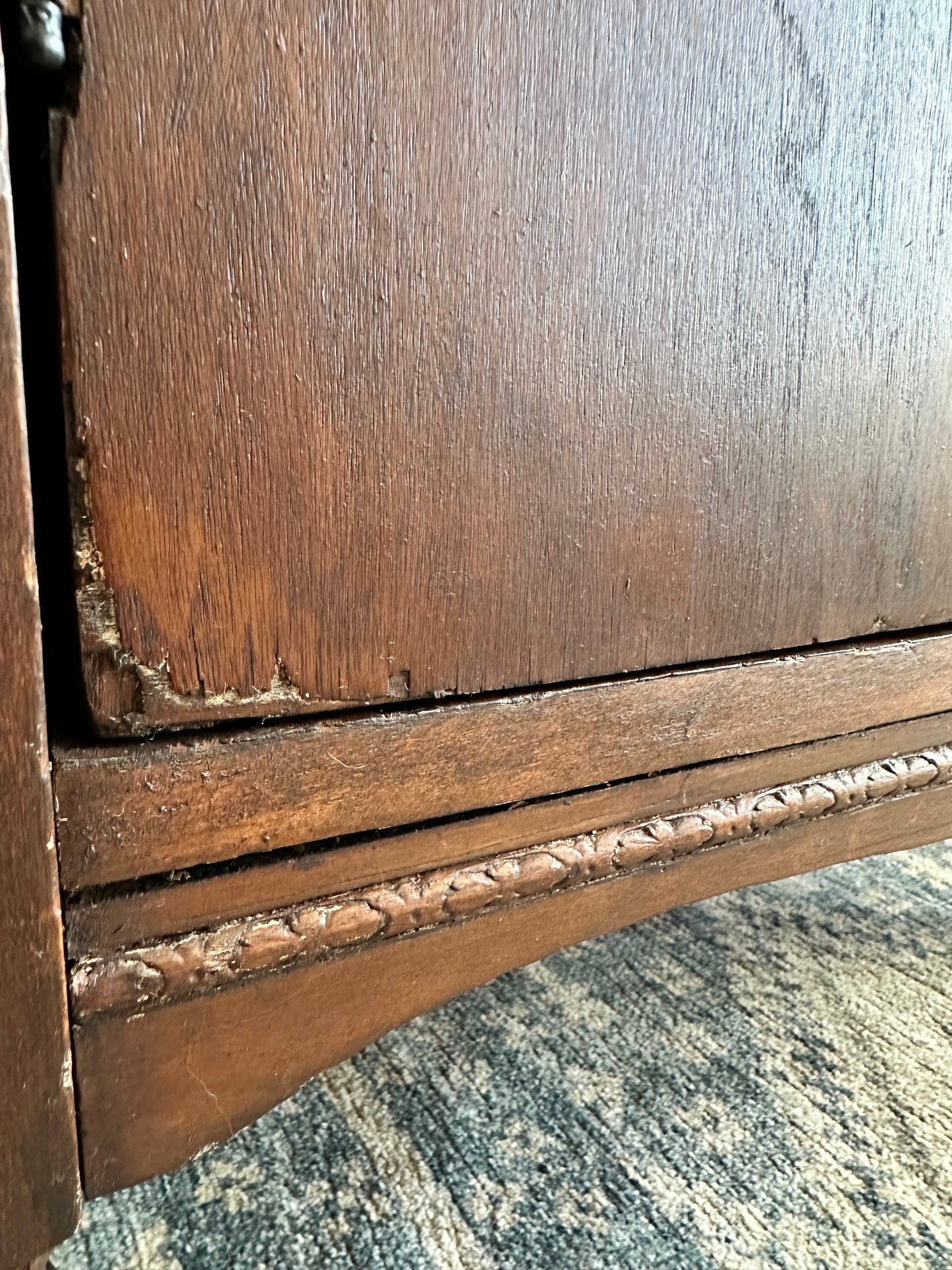 Close-up of a wooden surface with a decorative edge, possibly part of an antique piece of furniture.