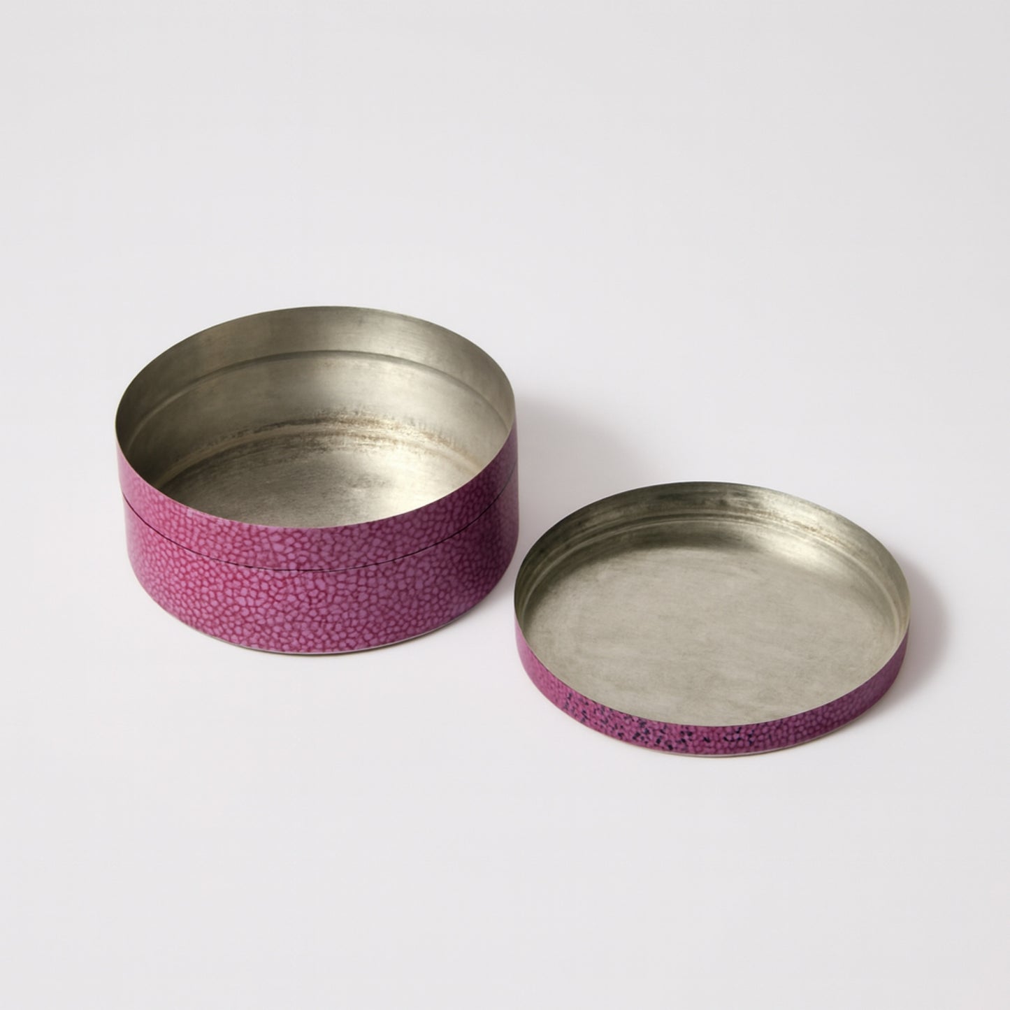 Two metallic containers with pinkish-purple textured bands on a white background