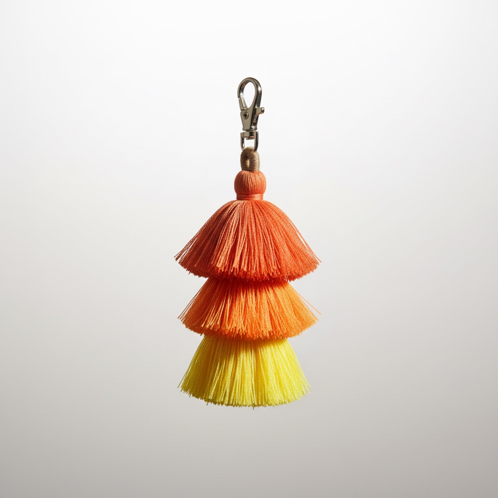 Colorful yellow orange crimson 
tassel keychain on a light gray background