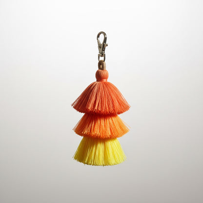 Colorful yellow orange crimson 
tassel keychain on a light gray background
