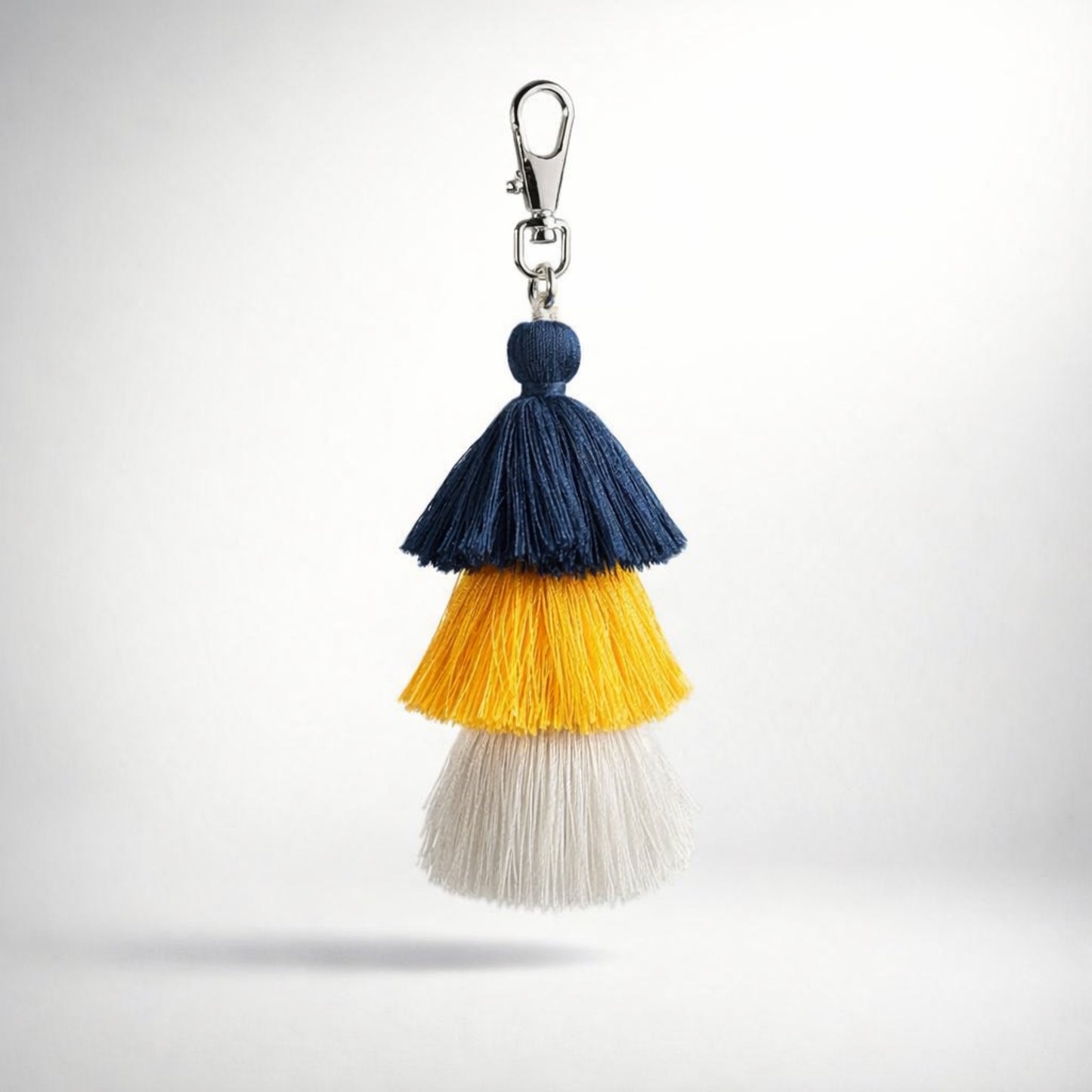 Colorful navy blue white yellow tassel keychain with a silver clasp on a white background