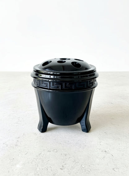Black ceramic pot with decorative design on a white background