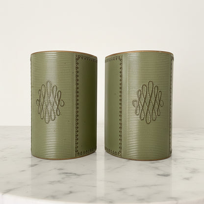 Pair of vintage mid-century sage green leather bookends featuring gold-tooled borders and central scroll monogram, displayed on a white marble surface.