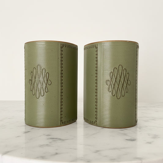 Pair of vintage mid-century sage green leather bookends featuring gold-tooled borders and central scroll monogram, displayed on a white marble surface.