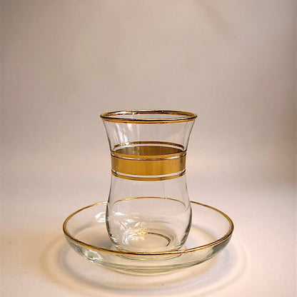 Elegant glass tea cup with gold accents and matching saucer, perfect for stylish tea service.
