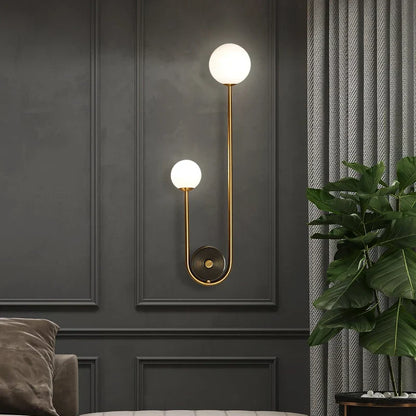 Elegant Modern Wall Lamp with Glass Ball Lampshade - LED Gold Luminaire Ideal for Home Decor, Living Room, Bedroom, and Interior Lighting Sconce with Nordic Flair Modern wall sconce with two lights on a dark gray wall with a plant and sofa in the background.
