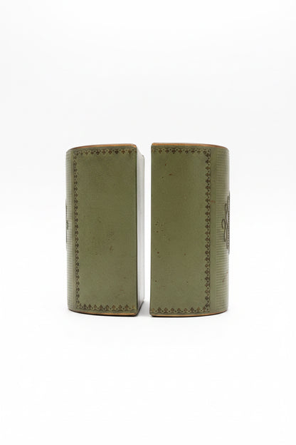 Side profile of a pair of vintage sage green leather bookends, showcasing the smooth leather finish and decorative gold tooling along the edges.