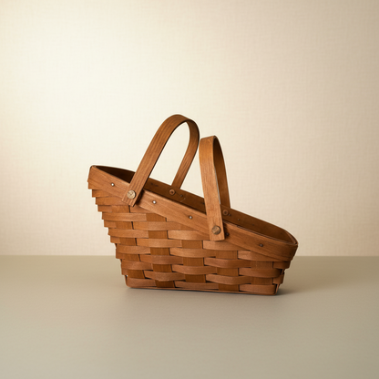 Side view of a vintage handwoven Longaberger wood splint basket with a slanted rim and dual upright handles.