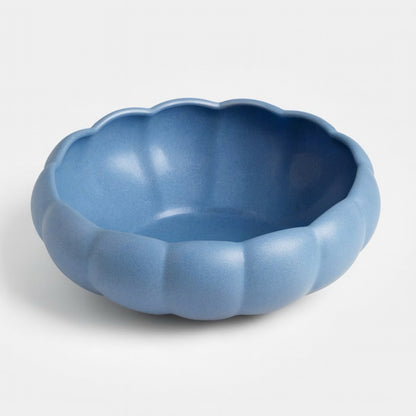 Top-down view of a sculptural blue ceramic bowl with rounded lobes and a matte glaze. The fluted design evokes floral and organic shapes, styled for modern vintage interiors.