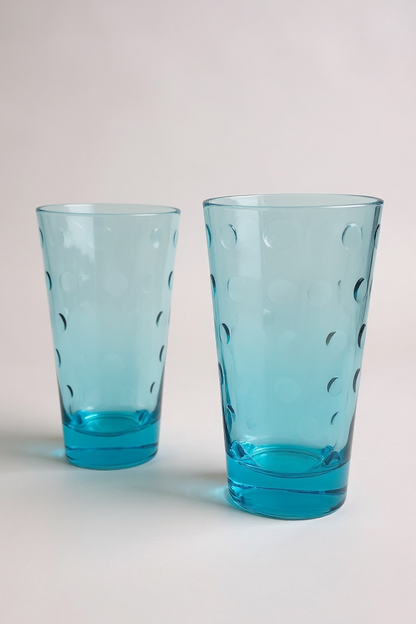 Two blue glass tumblers with a subtle pattern on a light gray background

