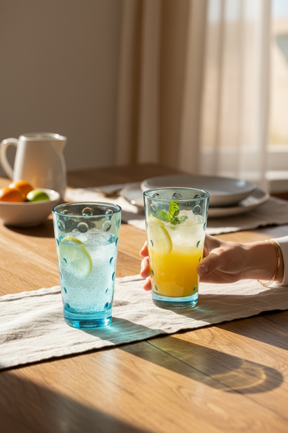 Two glasses of colorful drinks on a wooden table with a blurred background

