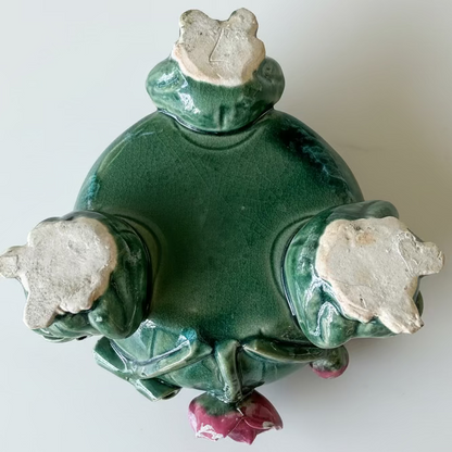 Unglazed bottom pads of three figural ceramic frog feet supporting a vintage majolica planter, showing a handwritten incised artisan character mark.