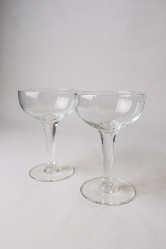 Elegant vintage-inspired coupe glasses, set of 2. Perfect for champagne, cocktails, or desserts. 5.5"H x 3.5"W clear glass. Timeless barware for entertaining and special occasions.