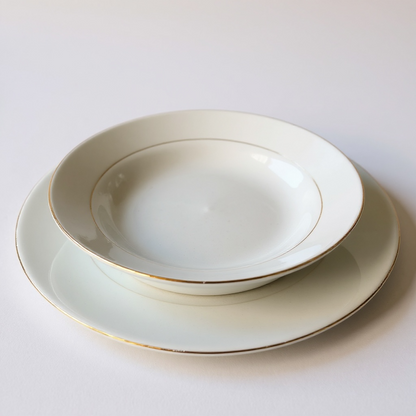Set of ceramic plates with gold rims on a white background


