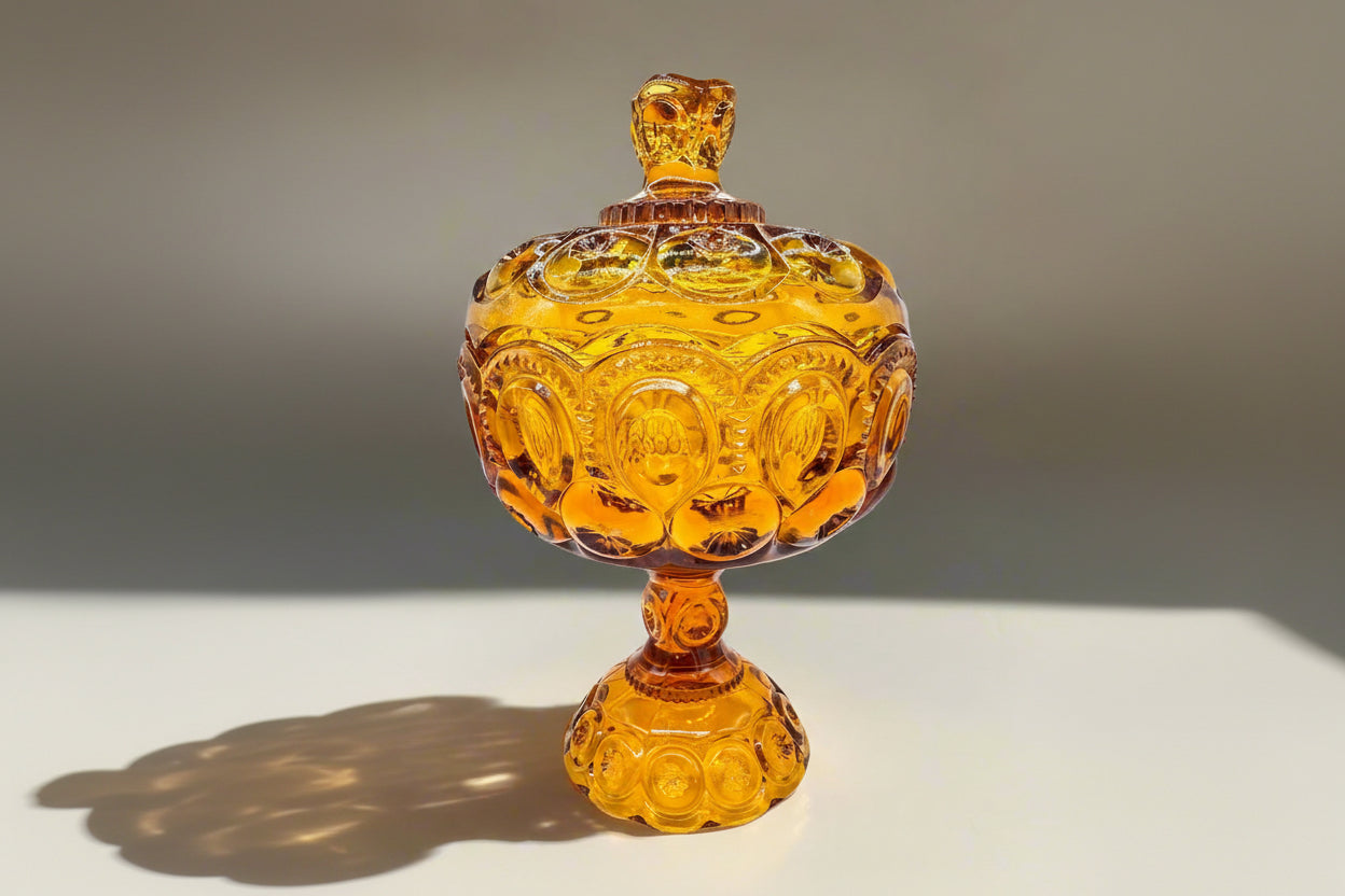 Vintage amber glass candy dish with ornate design and lid, perfect for home decor.