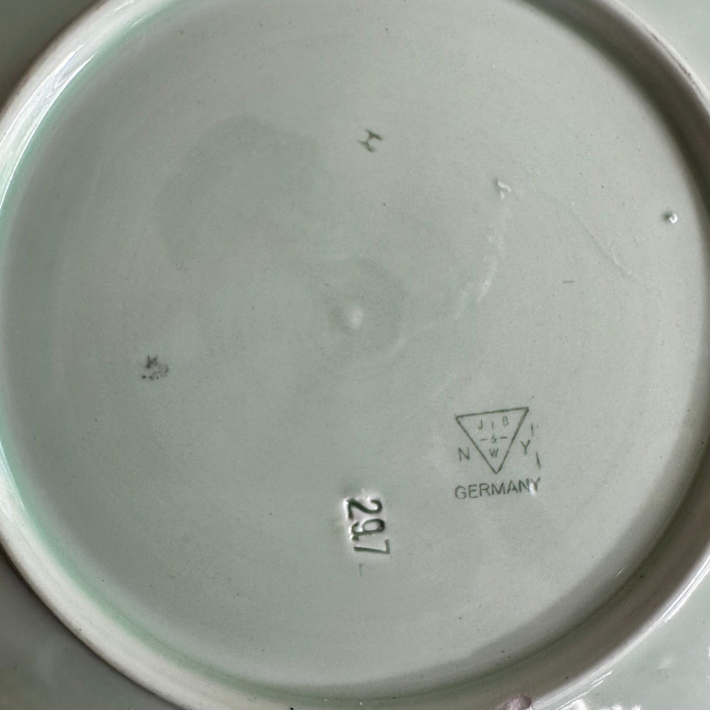 Vintage green ceramic plate with embossed markings, made in Germany.